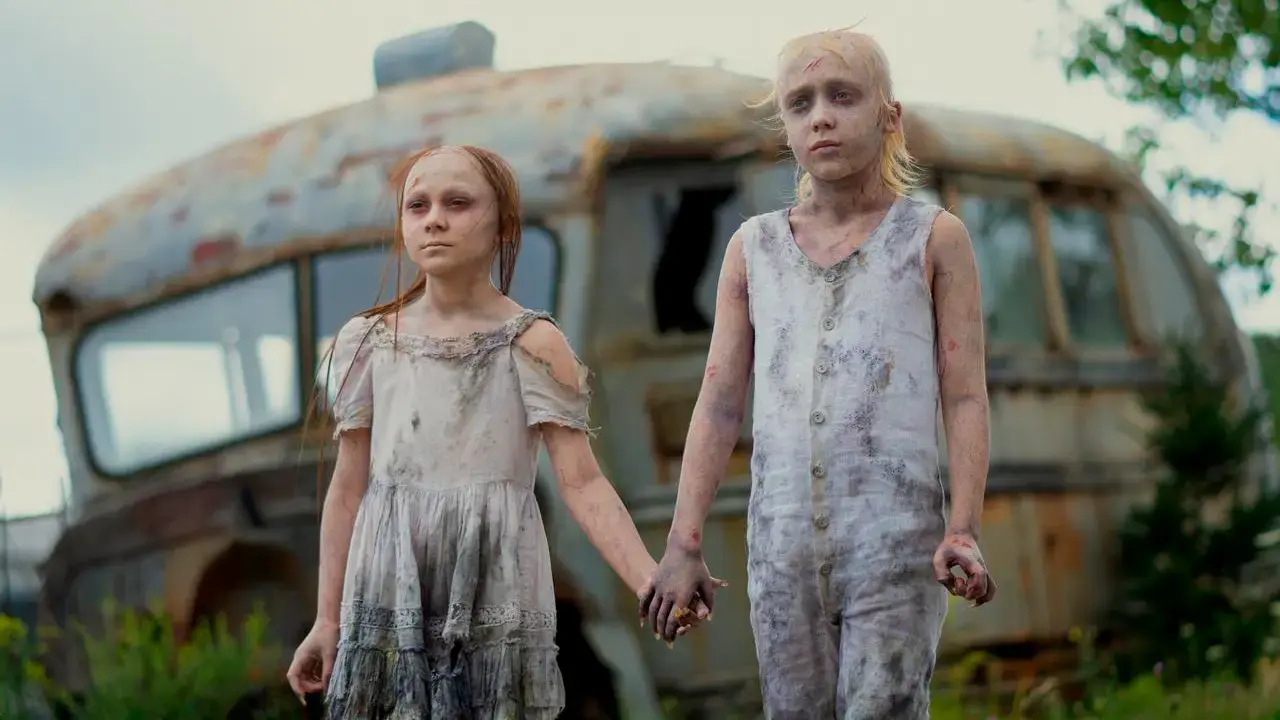 Deux enfants à l'aspect fantomatique se donnant la main, derrière il y a de la verdure et une voiture abandonnée.