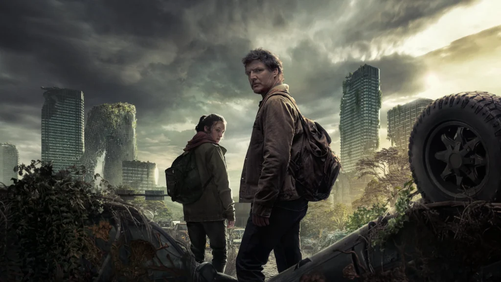 Image tirée de la série the last of us, on y voit les deux protagonistes au premier plan qui se retournent pour nous regarder, à l'arrière une ville américaine dévastée.
