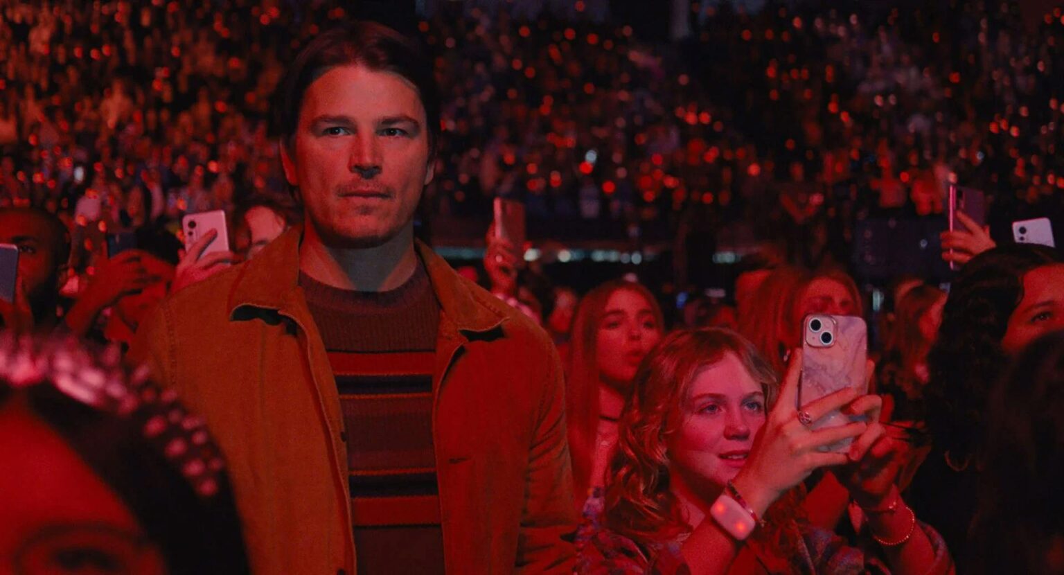 Josh Harnett, au concert avec sa fille, dans une ambiance tamisée et rouge.