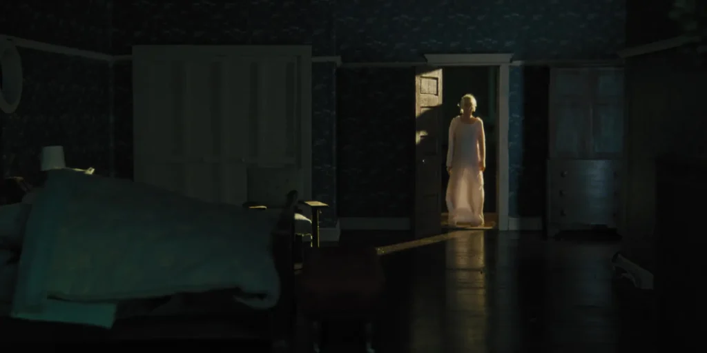La silhouette d'une vieille femme fantomatique se tient debout sur le seuil d'une chambre la nuit.