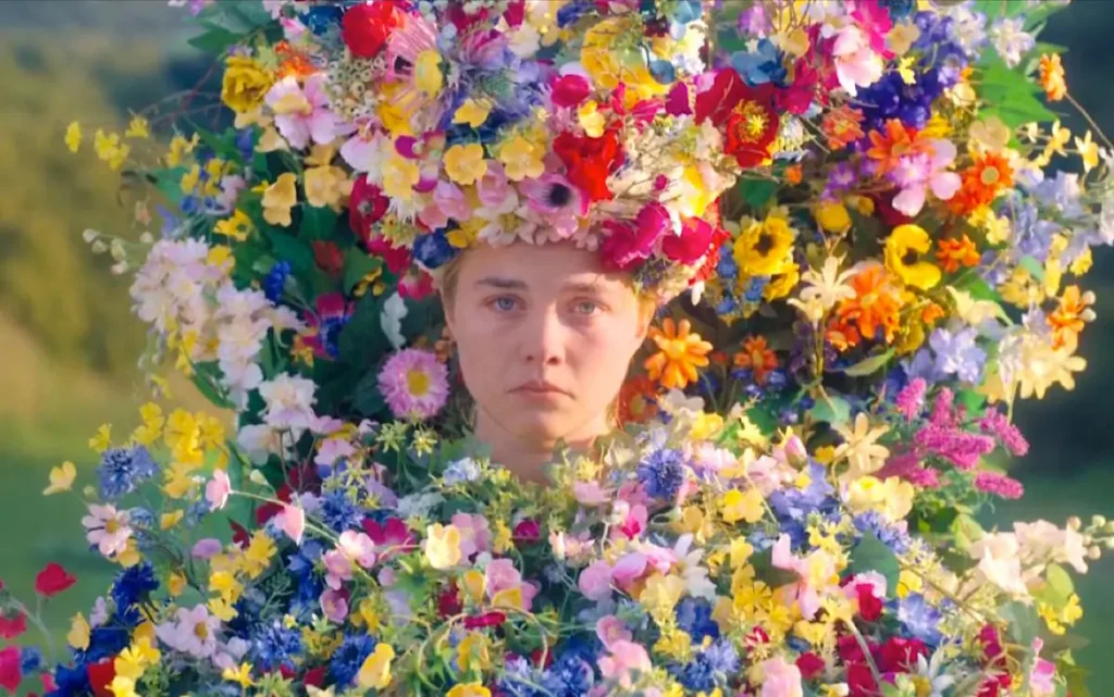 Une femme transformée en totem avec des milliers de fleurs jette un regard triste vers l'objectif.