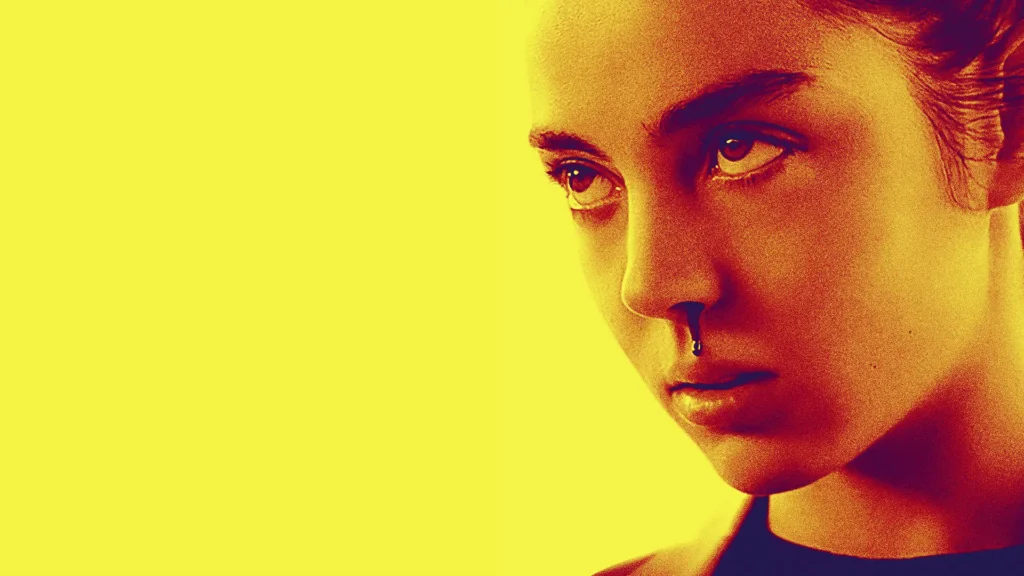 Le fond est jaune, sur la droite on y voit le visage d'une jeune femme le regard déterminée et le nez qui saigne.