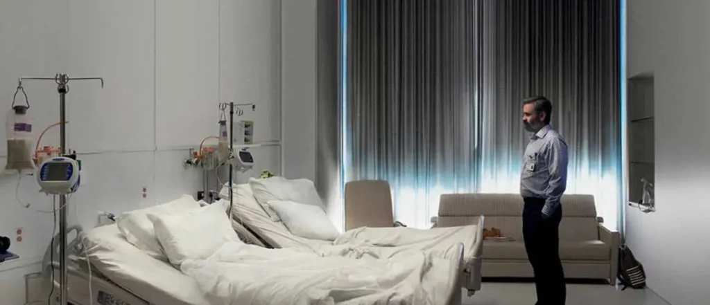 Un homme dans un hôpital regarde deux lit vide dans une image sui semble oppréssante.