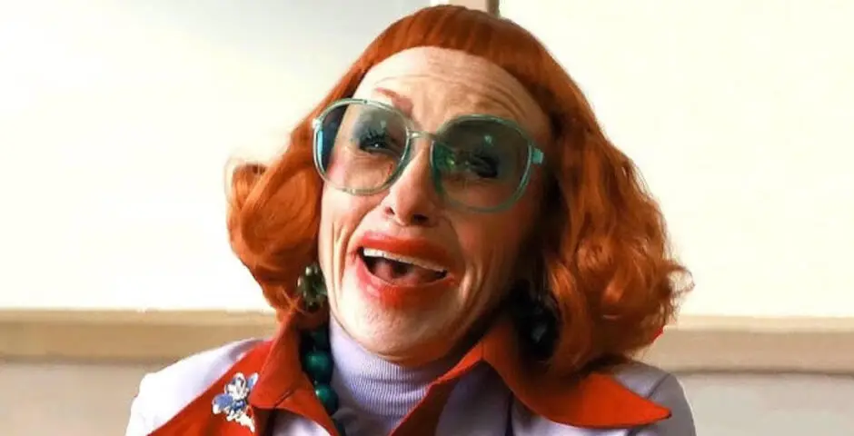 Une femme âgée très maquillée portant une perruque orange. Elle rappelle le clown maléfique dans It.