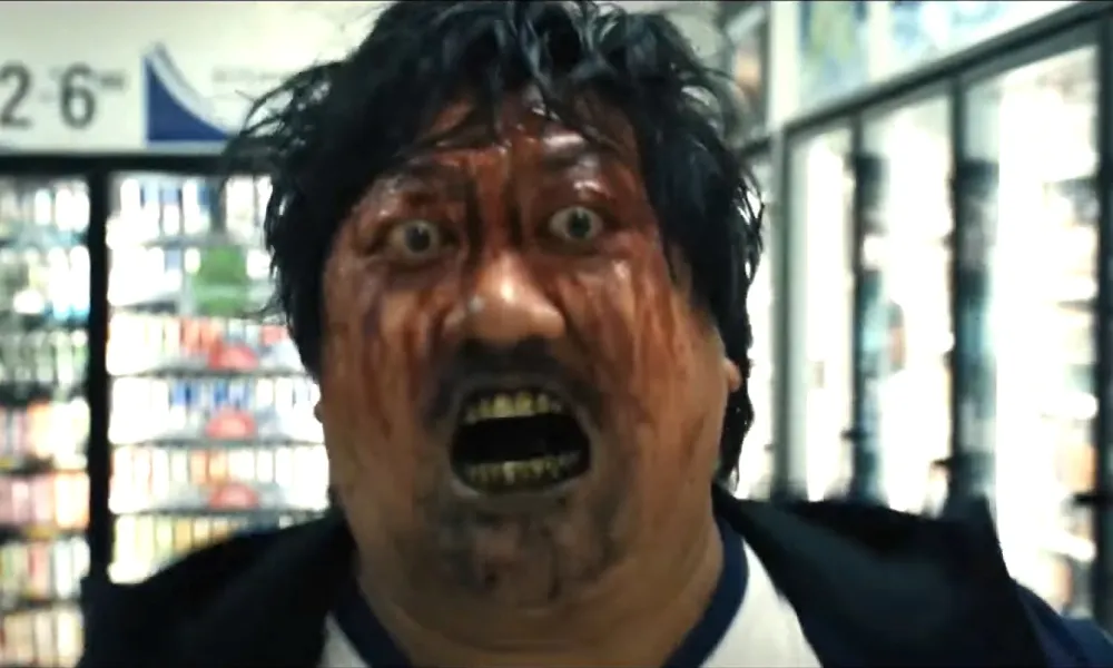 Un homme les yeux exorbités, du sang sur le visage et un liquide noir autour de la bouche jette un regard terrifiant devant lui.