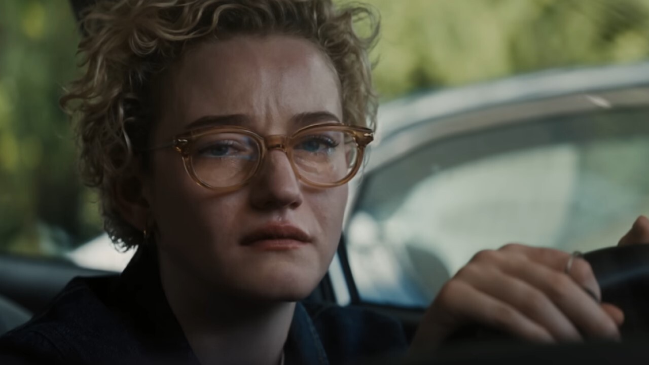 Une femme dans sa voiture à l'arrêt, les mains sur le volant, pleure.