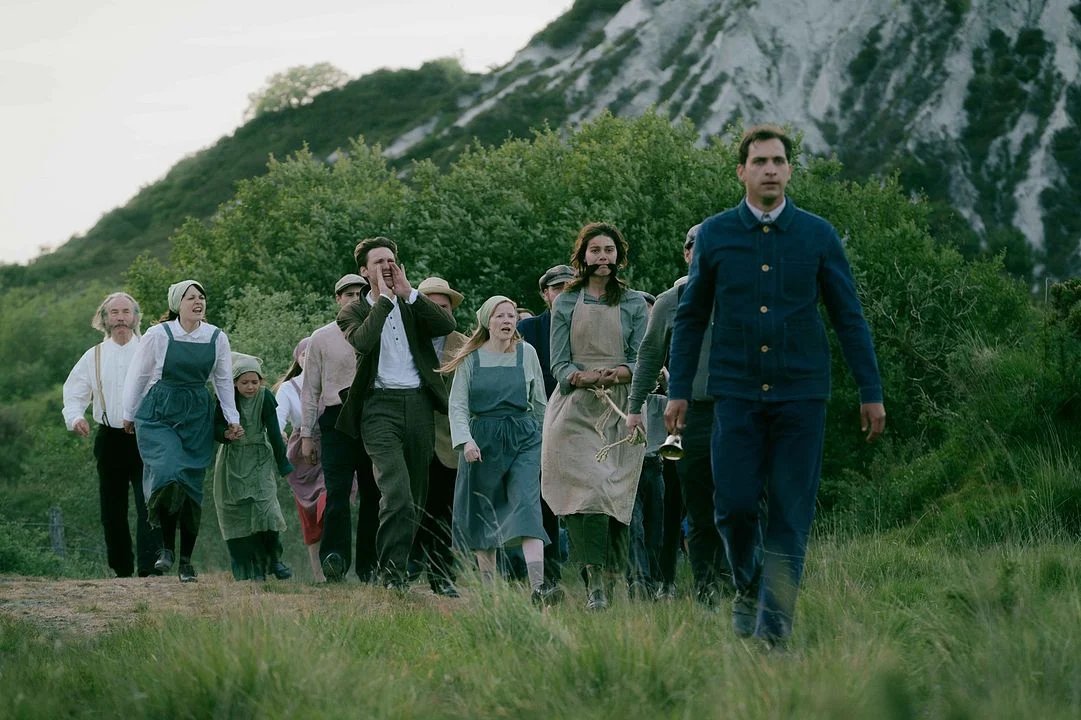 Des membres d'un village, mécontents, remontent une colline d'un pas pressé. Image tirée du film The Severed Sun.