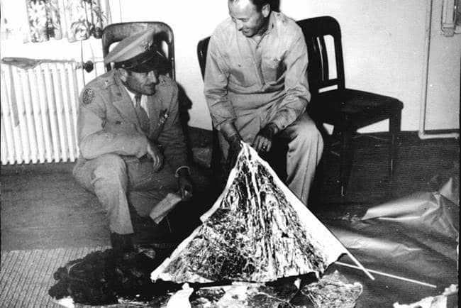 Archive de l'incident Roswell. On y un voit deux hommes collecter des débris et les manipuler au sein d'une maison.